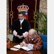 El nuevo Doctor Honoris Causa firma en el Libro de Honor de la Universidad ante la atenta mirada del rector.